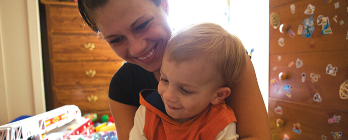 mom and son sitting on bed in childs room